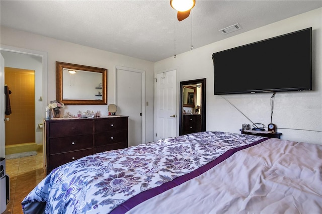 bedroom with tile patterned flooring, visible vents, a textured ceiling, and ceiling fan