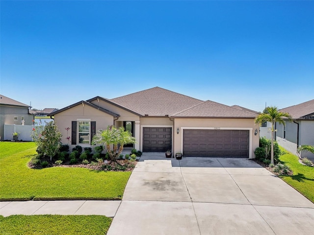 view of front facade featuring a front yard, concrete driveway, a garage, and stucco siding