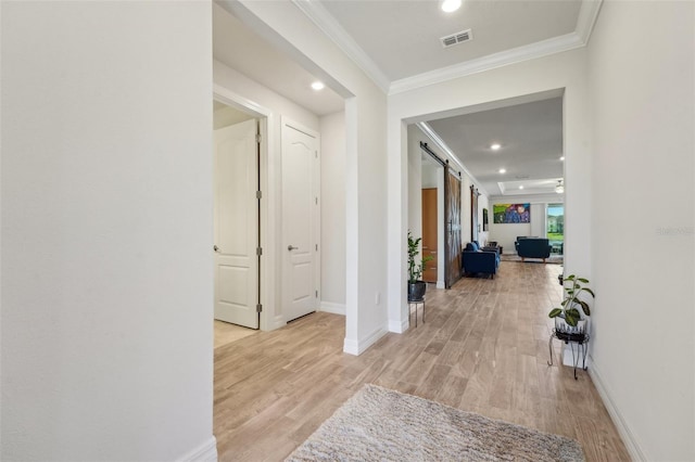 hall featuring baseboards, wood finished floors, a barn door, and ornamental molding