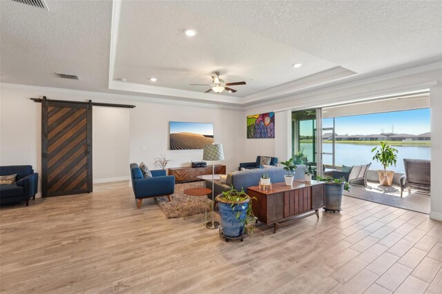 living room with a raised ceiling, a barn door, and wood finished floors