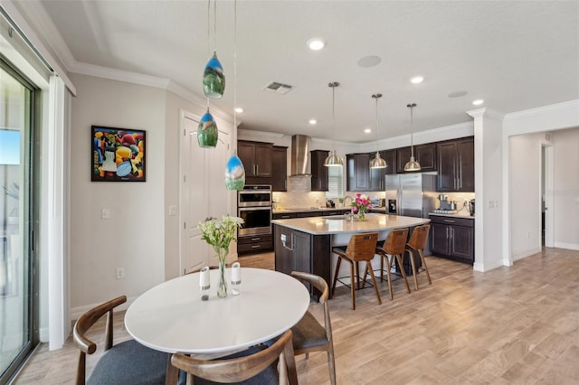 dining room with a wealth of natural light, visible vents, light wood-style flooring, and crown molding