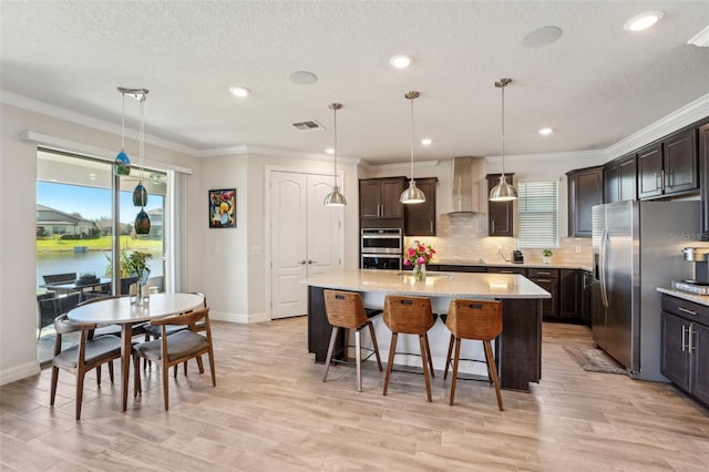 kitchen with visible vents, ornamental molding, stainless steel fridge, wall chimney exhaust hood, and decorative backsplash