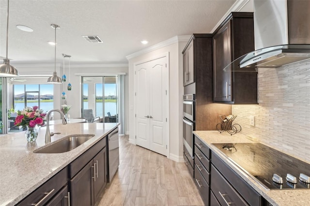 kitchen featuring visible vents, a sink, stainless steel dishwasher, black electric stovetop, and wall chimney exhaust hood