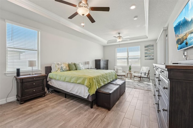 bedroom with a raised ceiling, light wood-style flooring, a ceiling fan, crown molding, and baseboards