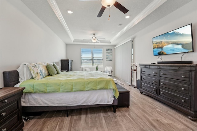 bedroom featuring light wood-type flooring, recessed lighting, crown molding, a raised ceiling, and ceiling fan