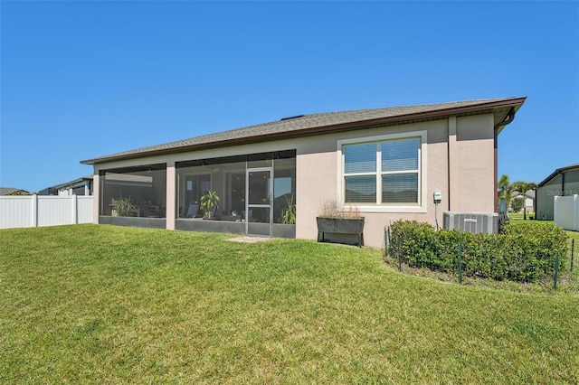 rear view of house featuring a lawn, fence, a sunroom, and stucco siding