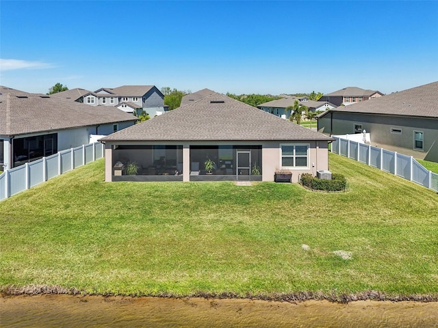 back of house featuring a lawn, a shingled roof, a fenced backyard, and a sunroom