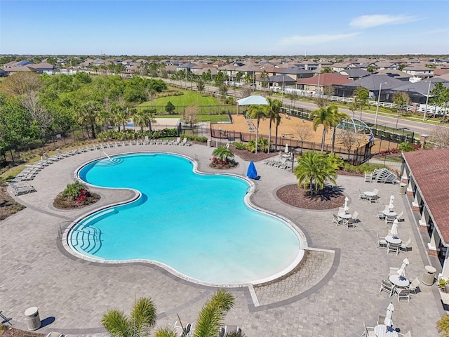 community pool featuring a patio area, fence, and a residential view