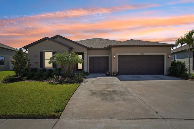 view of front of house featuring stucco siding, a lawn, roof with shingles, concrete driveway, and a garage