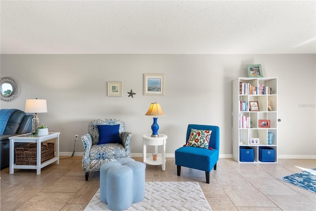 living area with tile patterned floors, baseboards, and a textured ceiling