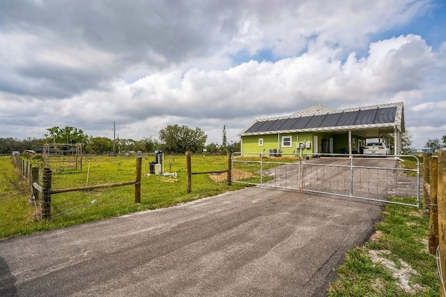 view of front facade with a gate, aphalt driveway, fence, a front yard, and an attached carport