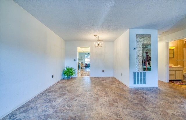 spare room with an inviting chandelier, visible vents, and a textured ceiling