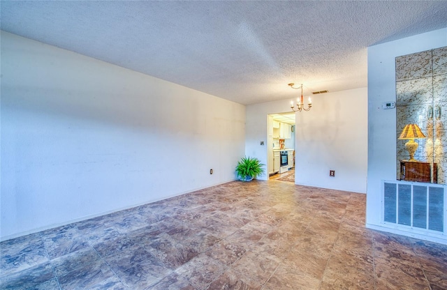 empty room featuring visible vents, a notable chandelier, and a textured ceiling