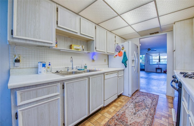 kitchen featuring tasteful backsplash, a drop ceiling, white appliances, and a sink