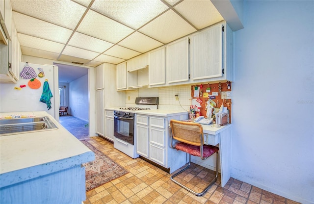 kitchen featuring a sink, white appliances, light countertops, decorative backsplash, and a paneled ceiling