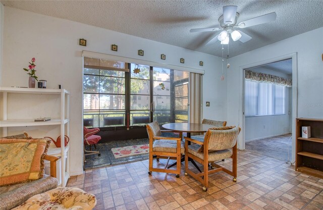 dining area with a textured ceiling, brick floor, and a ceiling fan