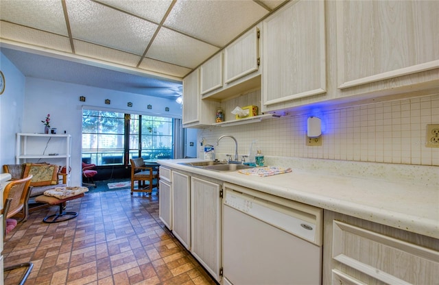 kitchen featuring brick floor, a sink, decorative backsplash, light countertops, and dishwasher