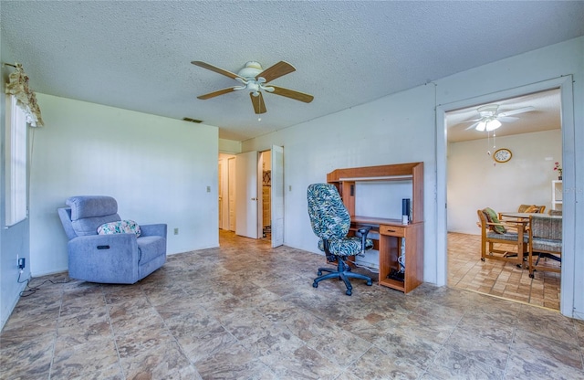 office area with visible vents, a textured ceiling, and a ceiling fan