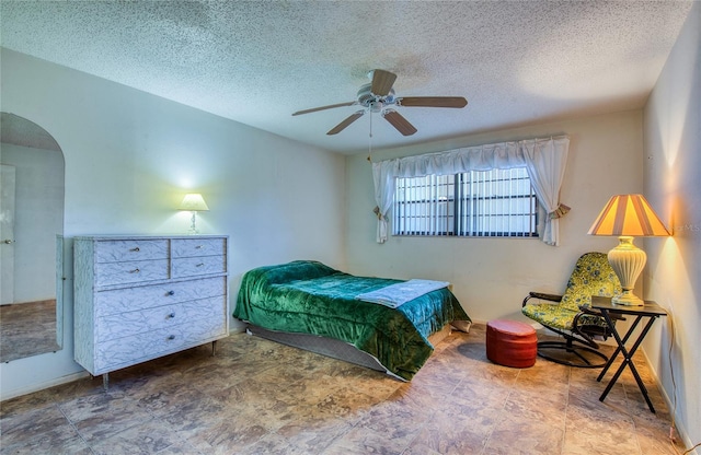 bedroom with arched walkways, a textured ceiling, and a ceiling fan