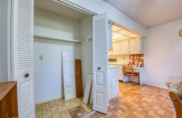 clothes washing area featuring laundry area, light floors, and a textured ceiling