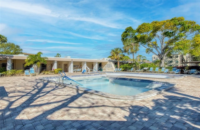 community pool with a patio area and fence