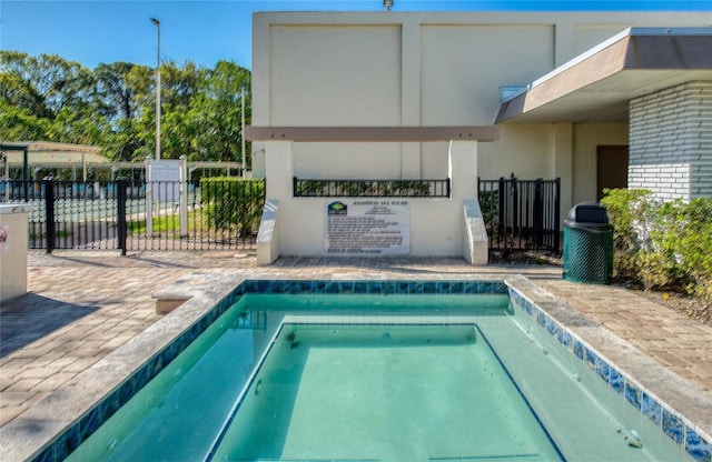 view of swimming pool with a community hot tub and fence