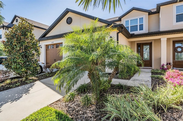 view of front of property featuring concrete driveway, an attached garage, and stucco siding