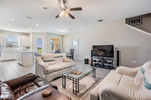 living area featuring light tile patterned flooring, baseboards, visible vents, and ceiling fan