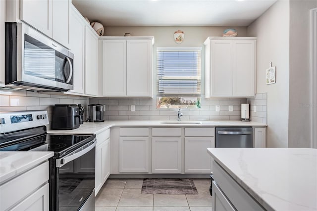 kitchen with a sink, backsplash, appliances with stainless steel finishes, and white cabinetry