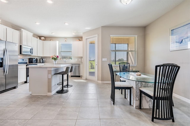 kitchen with tasteful backsplash, a center island, a breakfast bar area, white cabinets, and stainless steel appliances