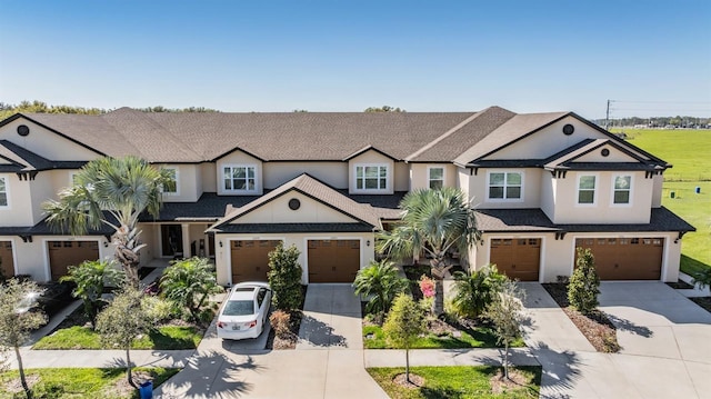 view of front of property featuring a shingled roof, concrete driveway, a garage, and stucco siding