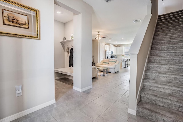 stairway with tile patterned floors, visible vents, baseboards, and ceiling fan