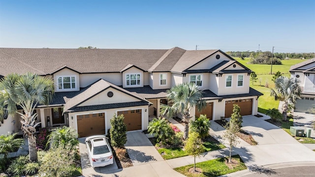 view of front of property with a shingled roof, an attached garage, driveway, and stucco siding