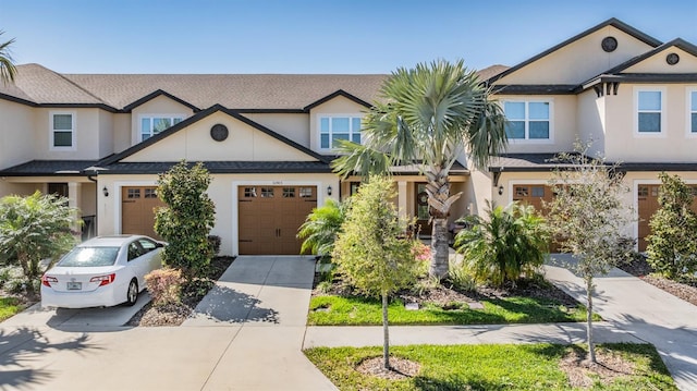 view of property with concrete driveway, an attached garage, and stucco siding