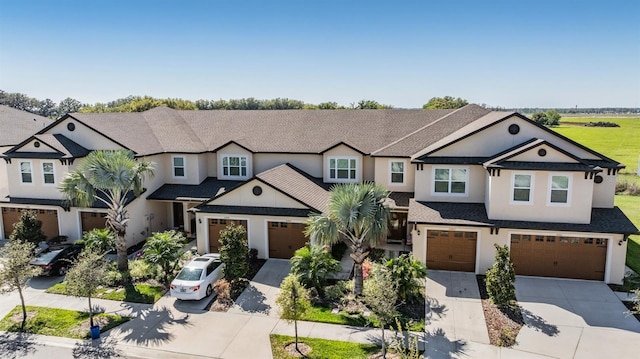 view of front of property with a shingled roof, concrete driveway, an attached garage, and stucco siding