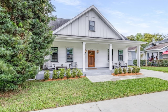 modern farmhouse featuring a front lawn, covered porch, and board and batten siding