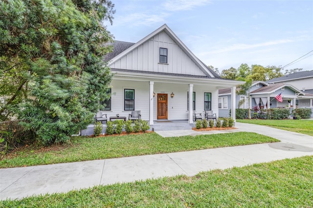 modern farmhouse featuring covered porch, board and batten siding, and a front lawn