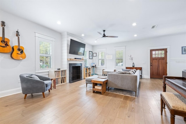 living room with visible vents, a fireplace with flush hearth, light wood-style floors, and a healthy amount of sunlight