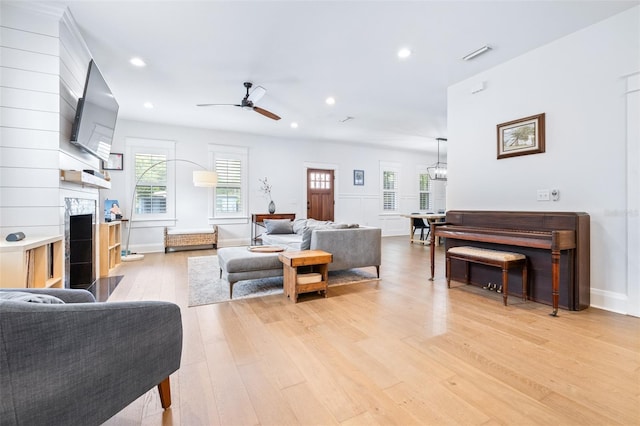 living area with a healthy amount of sunlight, visible vents, light wood finished floors, and a tile fireplace