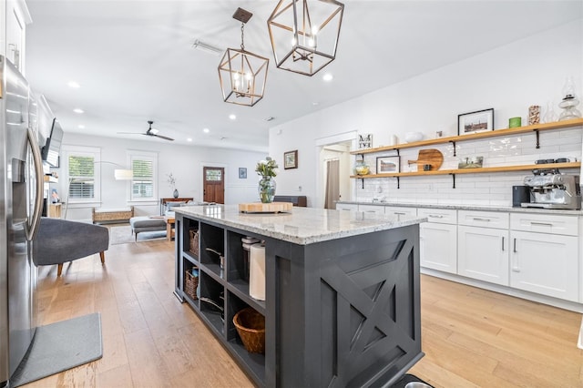 kitchen featuring stainless steel fridge, white cabinetry, and open shelves