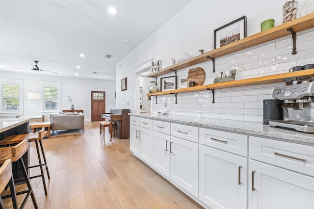 kitchen with light wood finished floors, decorative backsplash, white cabinetry, and open shelves