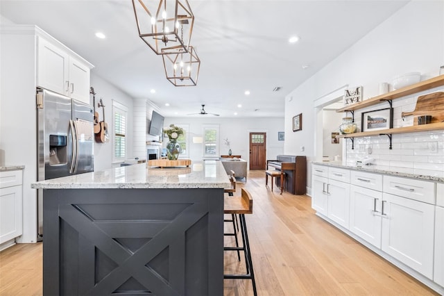 kitchen with a center island, light wood-type flooring, decorative backsplash, white cabinets, and open shelves