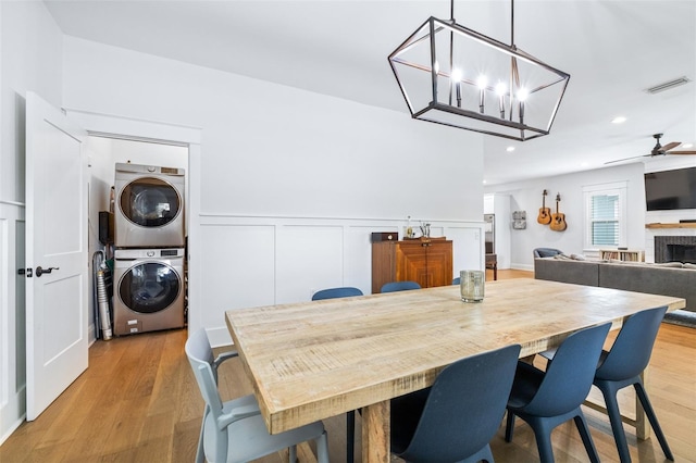 dining room featuring a wainscoted wall, stacked washer / dryer, visible vents, and light wood-type flooring