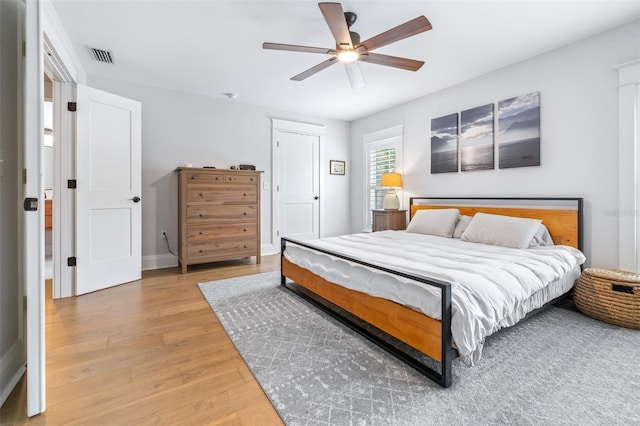 bedroom with light wood finished floors, visible vents, baseboards, and a ceiling fan