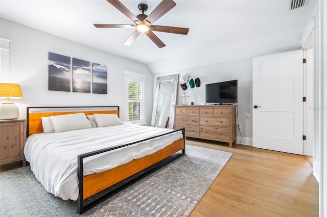 bedroom featuring visible vents, wood finished floors, a ceiling fan, and vaulted ceiling