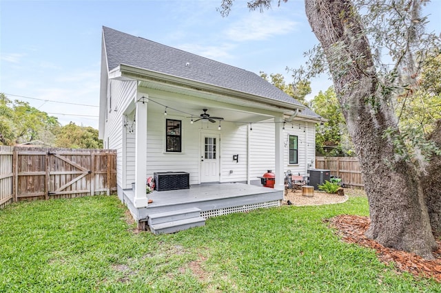 back of house with central AC, fence, a yard, a shingled roof, and ceiling fan