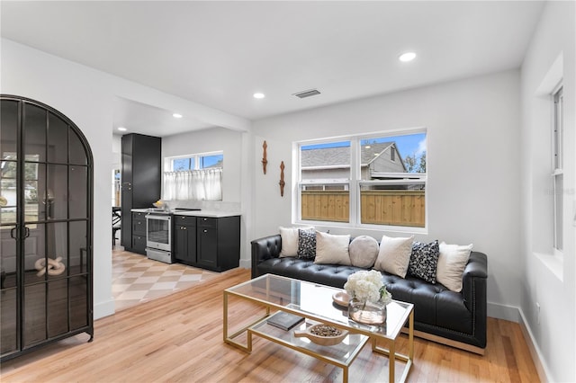 living area with recessed lighting, visible vents, light wood-type flooring, and baseboards