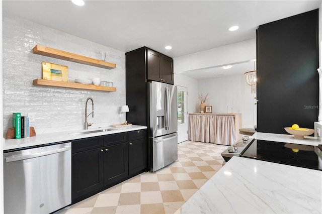 kitchen featuring a sink, dark cabinetry, stainless steel appliances, light stone countertops, and light floors