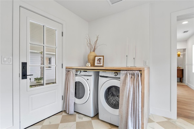 laundry room with washer and dryer, visible vents, baseboards, and light floors