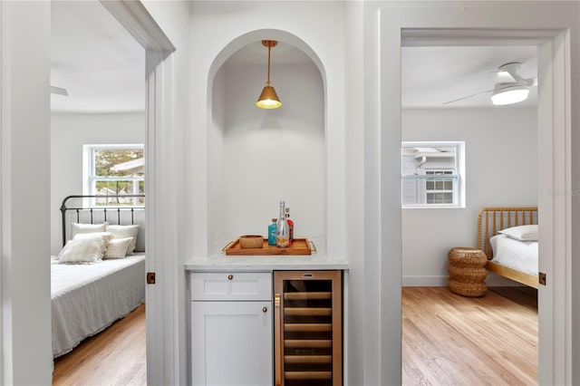 bar with wine cooler, hanging light fixtures, a dry bar, and wood finished floors